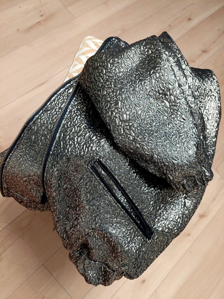 Veste Blossom en jacquard doré et noir posée sur un tabouret